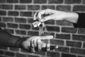 Real estate agent hands over a keychain to a home buyer LUX. Denver Colorado luxury real estate company